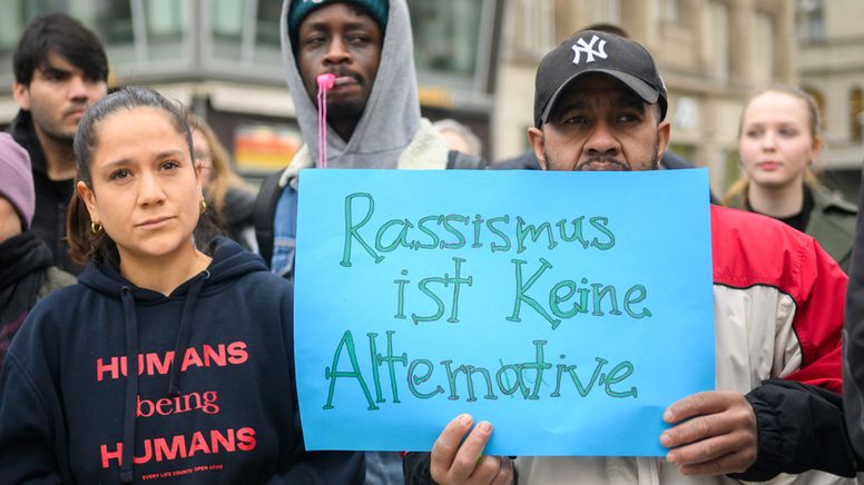 Ein Demonstrant hält ein mit der Hand bemaltes Schild in die Kamera auf der der Slogan: "Rassismus ist keine Alternative" steht. Er steht in einer Gruppe von Demonstrantinnen und Demonstranten zum Internationalen Tag gegen Rassismus | Bild:dpa-Bildfunk/ Julian Stratenschulte