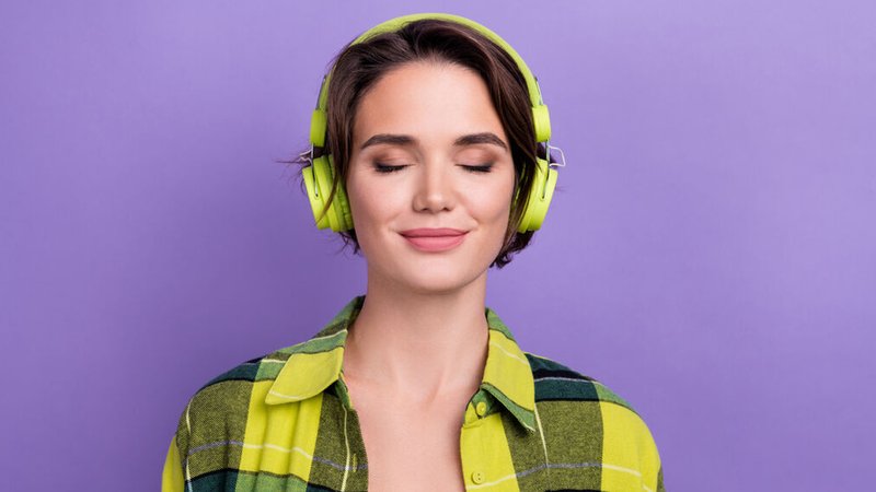 Eine Frau hört mit geschlossenen Augen Musik auf ihren Kopfhörern. | Bild: stock.adobe.com/deagreez Eine Frau hört mit geschlossenen Augen Musik auf ihren Kopfhörern.