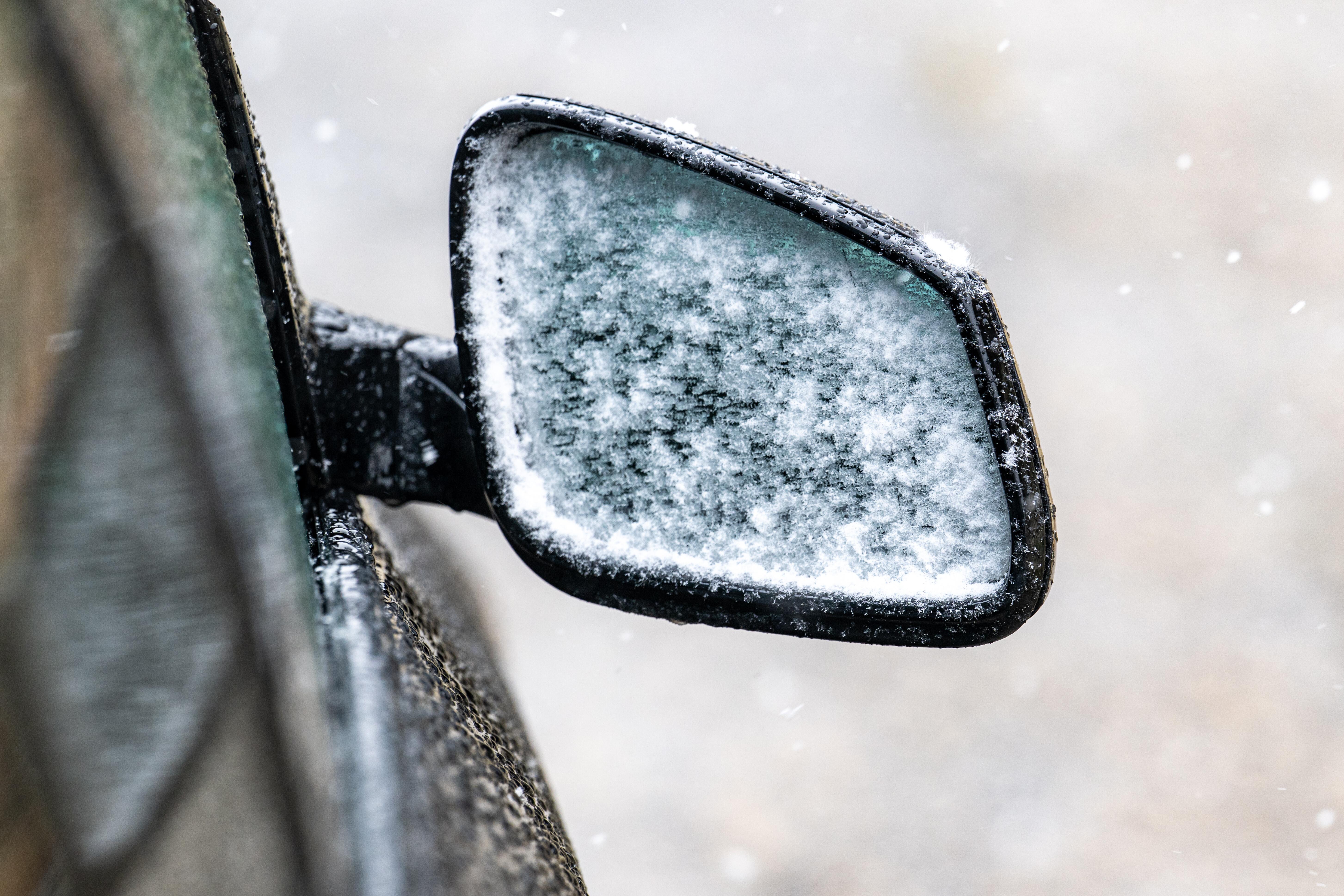 Schnee haftet am Außenspiegel eines Autos. 