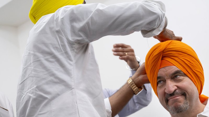 Markus Söder (CSU), Ministerpräsident von Bayern, bekommt zu Beginn seines Besuchs des Sikh-Tempels "Gurudwara Bangla Sahib" einen orangenen Turban. Söder befindet sich auf einer mehrtägigen Indienreise. | Bild: dpa-Bildfunk/Peter Kneffel Markus Söder (CSU), Ministerpräsident von Bayern, bekommt zu Beginn seines Besuchs des Sikh-Tempels "Gurudwara Bangla Sahib" einen orangenen Turban. Söder befindet sich auf einer mehrtägigen Indienreise.
