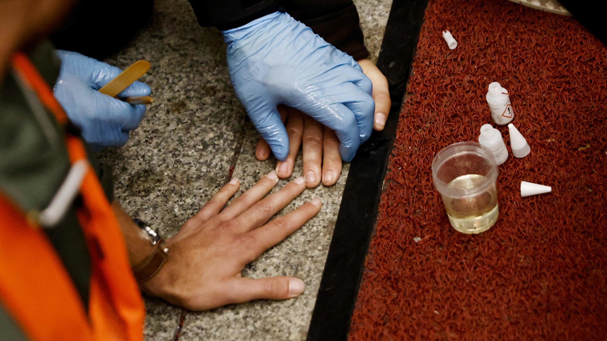 Ein Polizist versucht, die von einem Aktivisten am Boden angeklebte Hand zu lösen (Archivbild).