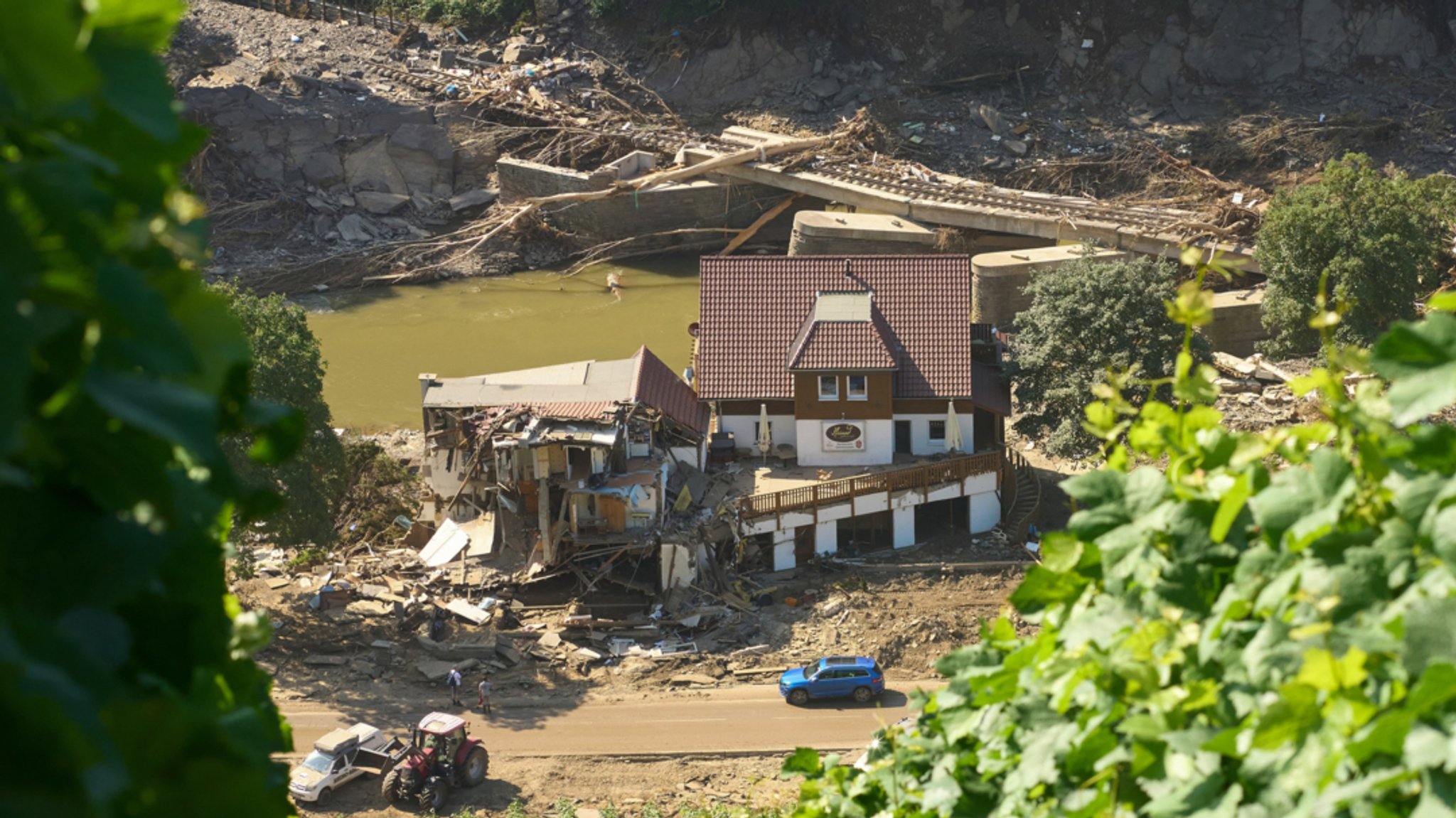 Rheinland-Pfalz, Marienthal: Ein Haus ist nach dem Hochwasser vollkommen aufgerissen, dahinter ist eine zerstörte Brücke zu sehen.