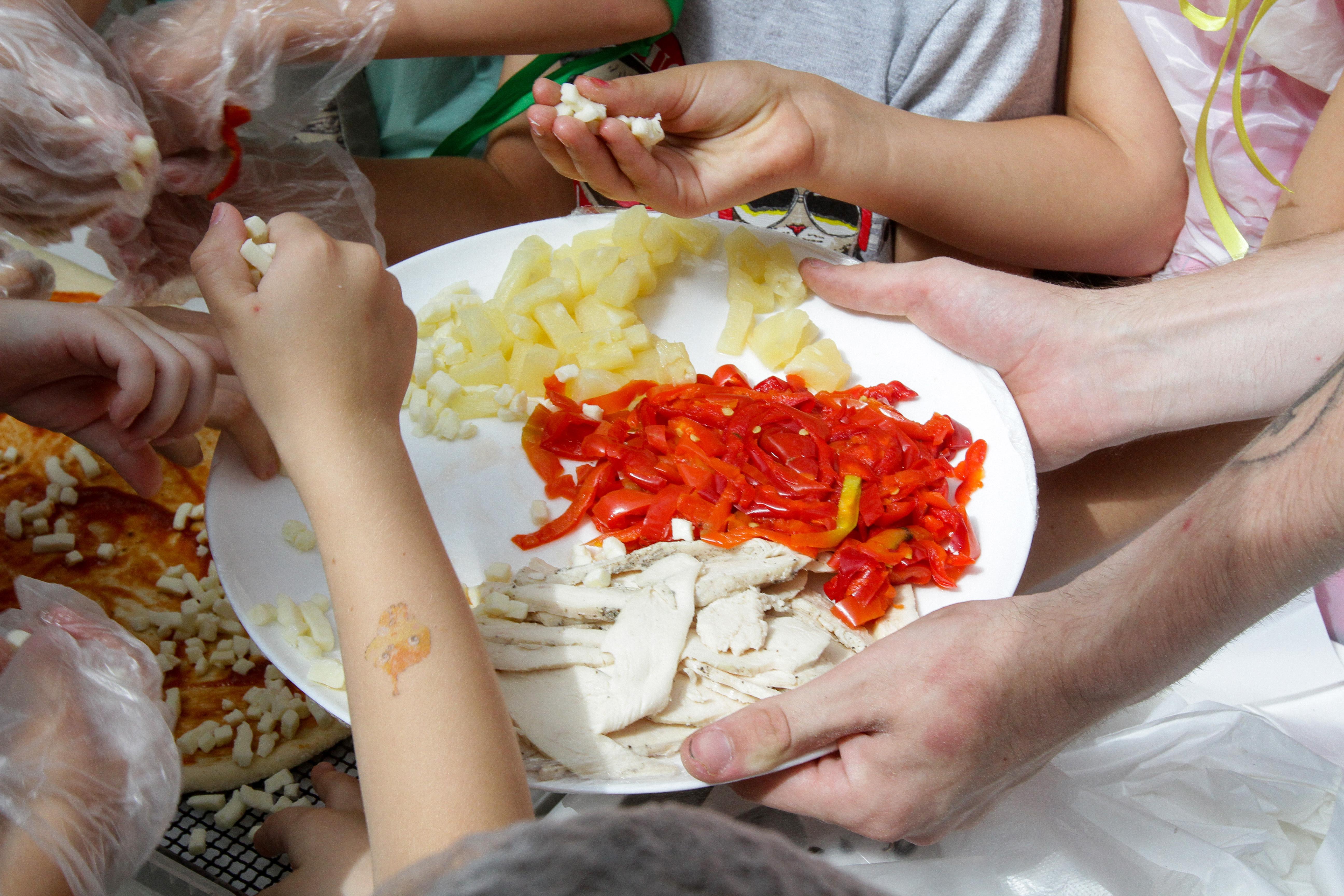Kinder aus der Ukraine belegen gemeinsam eine Pizza (Symbolbild)