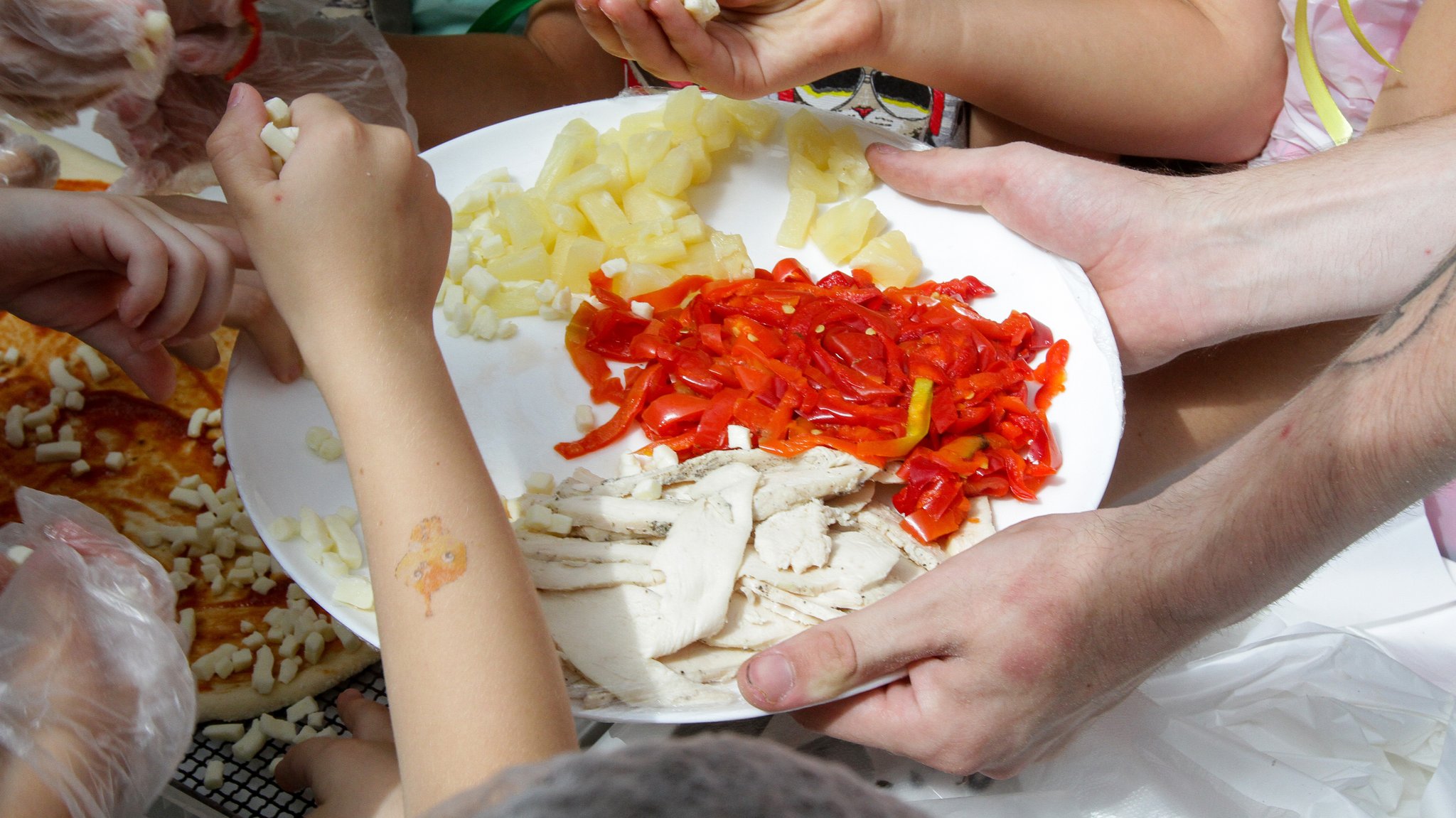 Kinder aus der Ukraine belegen gemeinsam eine Pizza (Symbolbild)