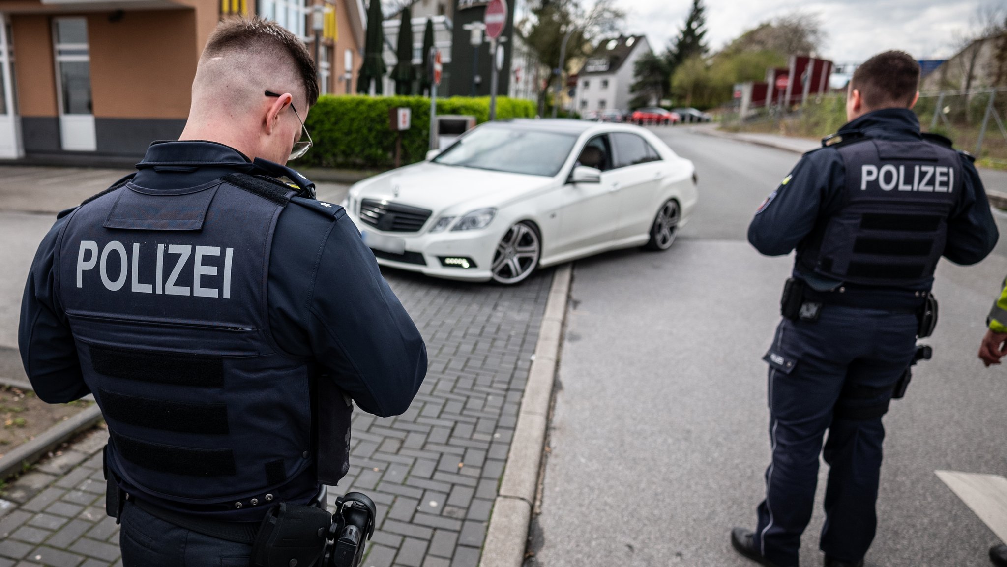 Zwei Polizisten gehen auf ein Auto zu