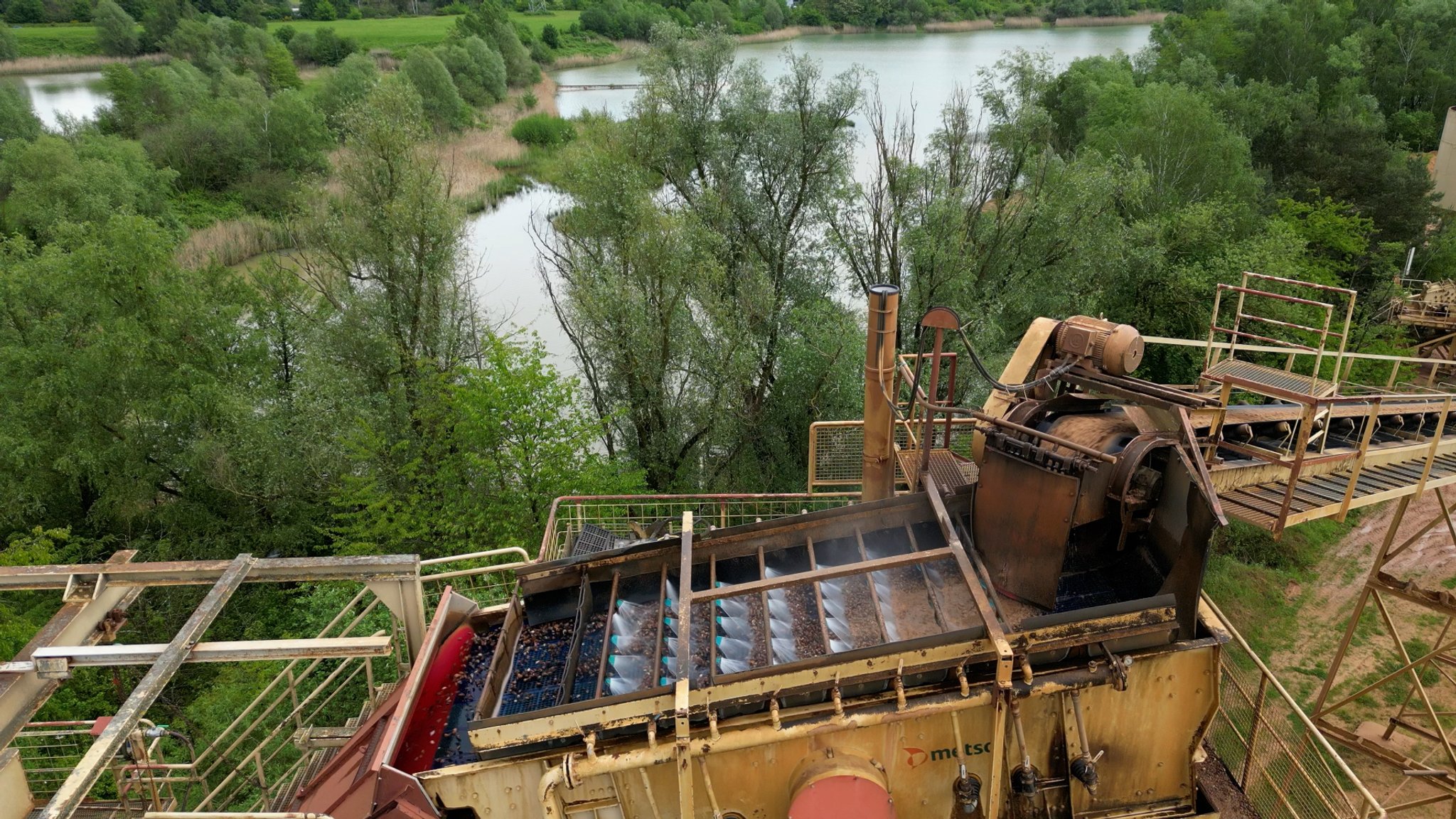 Das abgebaggerte Kies wird mit Wasser aus dem im Bild sichtbaren See gewaschen, bevor es in ein Silo kommt.