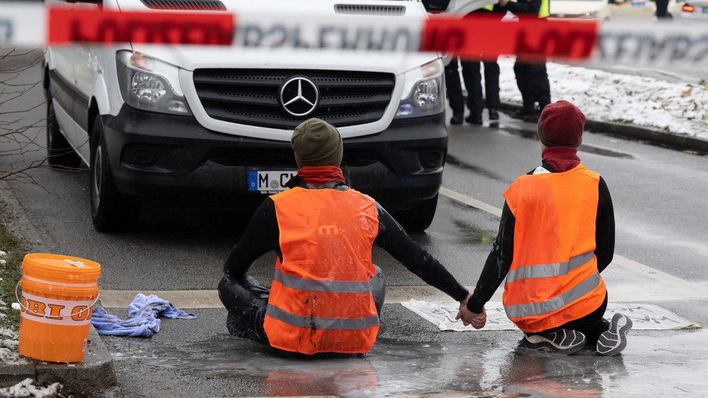 Klimaaktivisten blockieren eine Straße in München. Das Festkleben an der Fahrbahn scheiterte an der Witterung.