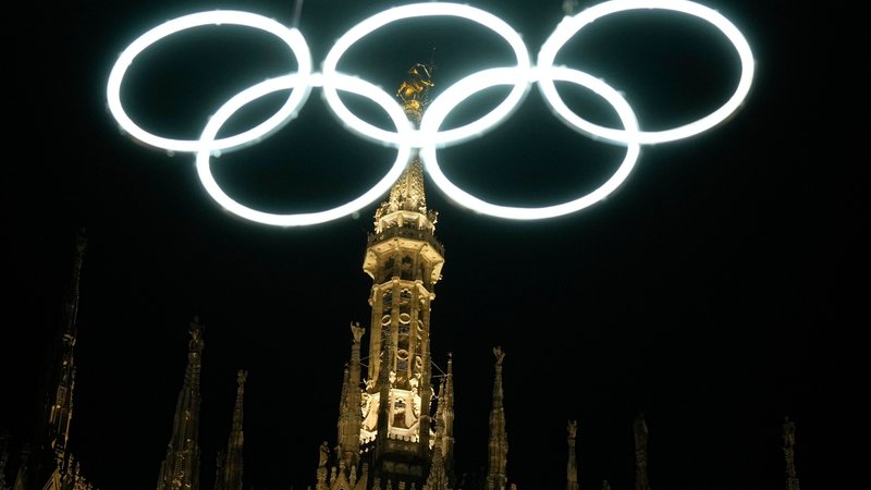 27.12.2025, Italien, Mailand: Olympische Ringe leuchten neben dem gotischen Dom für die bevorstehenden Olympischen Winterspiele in Mailand. Foto: Luca Bruno/AP/dpa +++ dpa-Bildfunk +++ | Bild: dpa-Bildfunk/Luca Bruno 27.12.2025, Italien, Mailand: Olympische Ringe leuchten neben dem gotischen Dom für die bevorstehenden Olympischen Winterspiele in Mailand. Foto: Luca Bruno/AP/dpa +++ dpa-Bildfunk +++