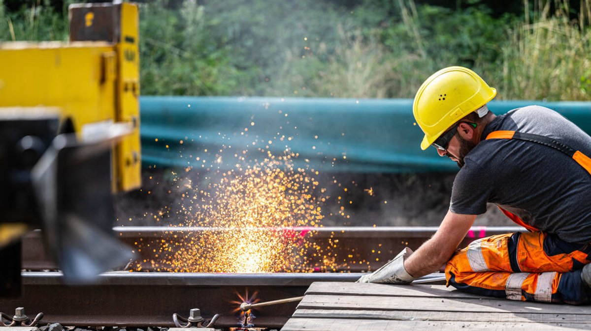 Symbolbild Bahnbauarbeiten: Ein Bauarbeiter trennt mit einem Schweißbrenner die Bahngleise durch.