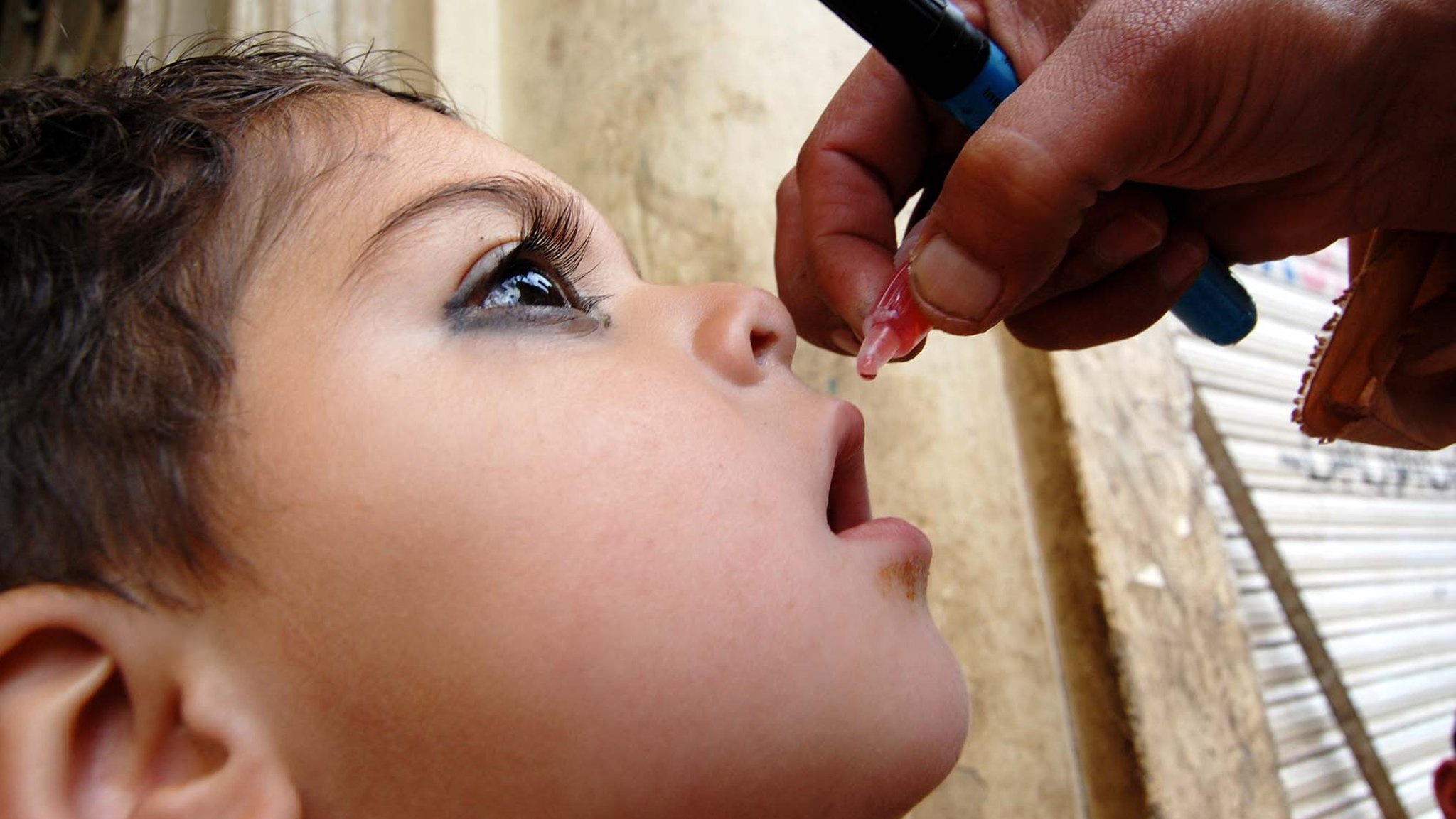 Ein Mädchen bekommt einen Schluckimpfung gegen Polio.