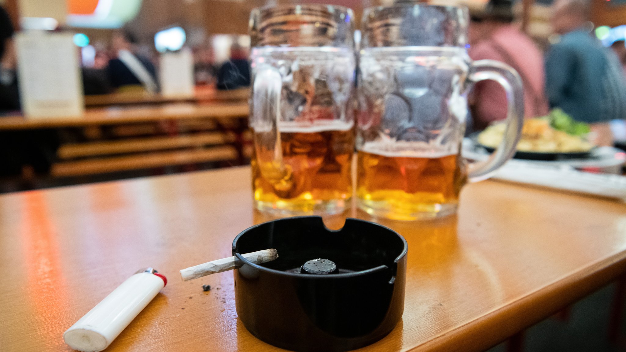 Ein Aschenbecher und Bierkrüge stehen auf einer Bierzelt-Bank.