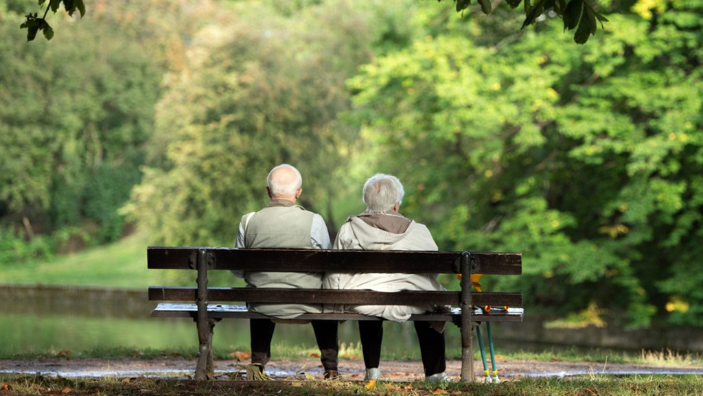 Ein Rentner-Ehepaar sitzt auf einer Bank 