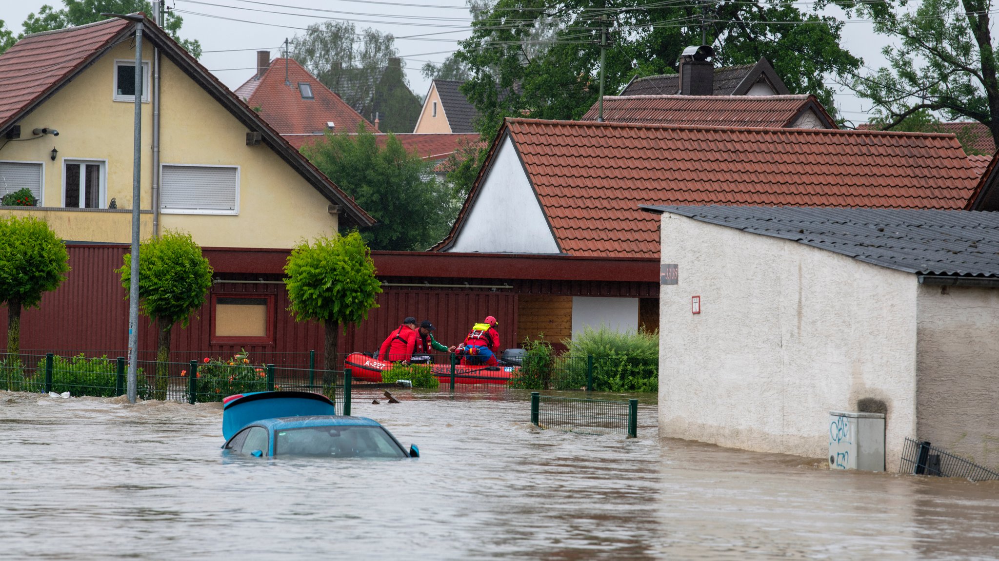 Die Wasserwacht fährt mit einem Schlauchboot durch eine überflutete Straße. Nach den ergiebigen Regenfällen der letzten Tage gibt es Hochwasser in der Region.