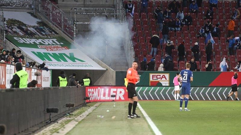 Eine Rauchwolke am Gästeblock nach einer lauten Explosion während des Spiels FC Augsburg gegen 1890 Hoffenheim