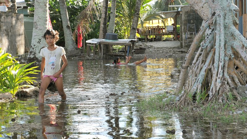 Mädchen watet durch überschwemmten Teil von Funafuti, der Hauptstadt von Tuvalu. | Bild: picture alliance / Kyodo Mädchen watet durch überschwemmten Teil von Funafuti, der Hauptstadt von Tuvalu.