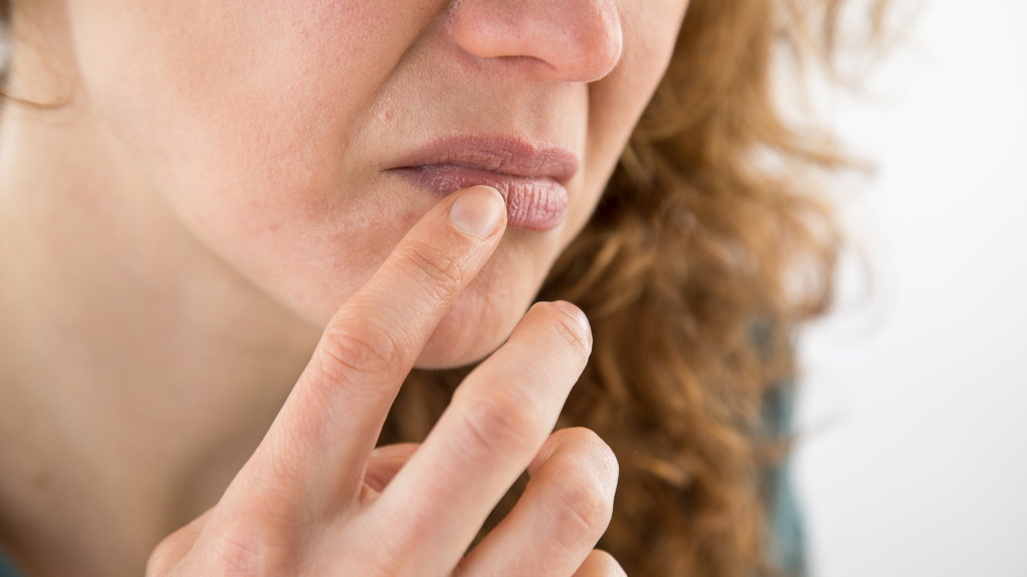 Frau fasst sich mit dem Finger an den verzerrten Mund. | Bild: picture-alliance/dpa/Christin Klose Frau fasst sich mit dem Finger an den verzerrten Mund.