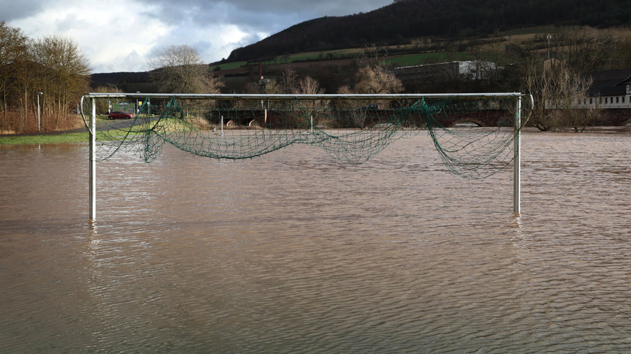 03.01.2024, Bayern, Markt Euerdorf: Ein Tor steht auf einem vom Hochwasser der Fränkischen Saale überschwemmten Fußballplatz.