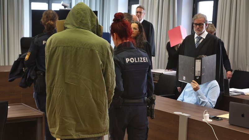 Zum Prozessbeginn im Januar: Der wegen Mordes angeklagte Mann steht im Gerichtssaal am Landgericht Memmingen neben einer Polizistin