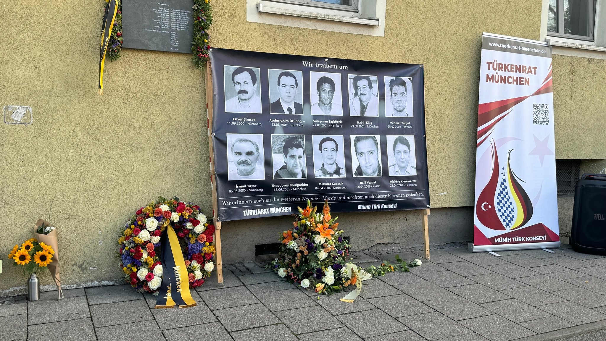 Blumengestecke von der Stadt München, der Beratungsstelle Before und Blumen von Privatpersonen an einer Gedenktafel für die NSU-Opfer in München. | Bild: BR/Katrin Bohlmann Blumengestecke von der Stadt München, der Beratungsstelle Before und Blumen von Privatpersonen an einer Gedenktafel für die NSU-Opfer in München.
