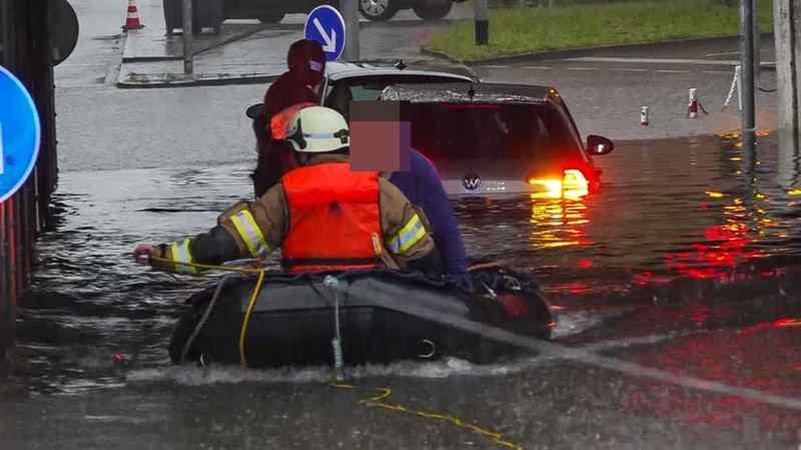 Ein Mann sitzt in einem Schlauchboot der Feuerwehr, die ihn aus einem Auto in einer vollgelaufenen Unterführung gerettet hat.