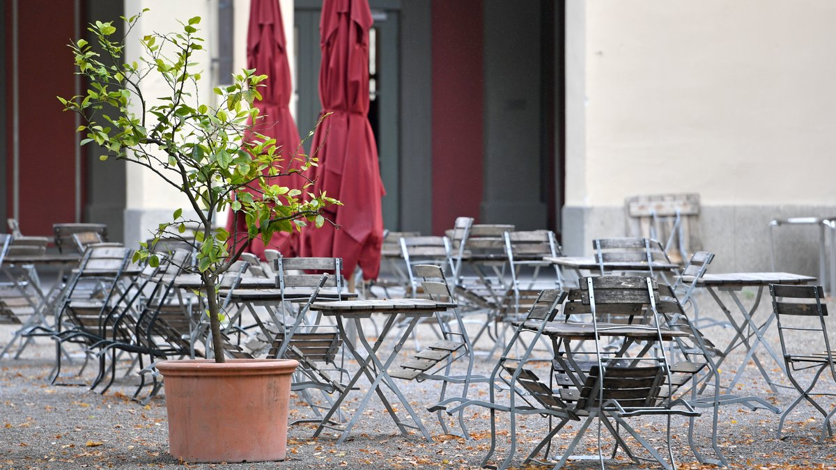 Leere, unbesetzte freie Stühle und Tische im Außenbereich eines Restaurants in München. 