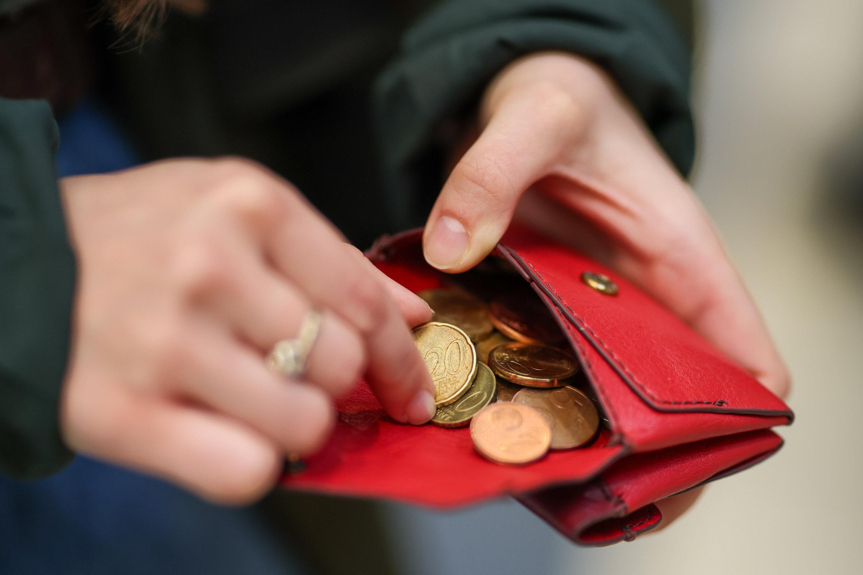 Eine Frau zählt Münzen aus einem roten Portemonnaie.