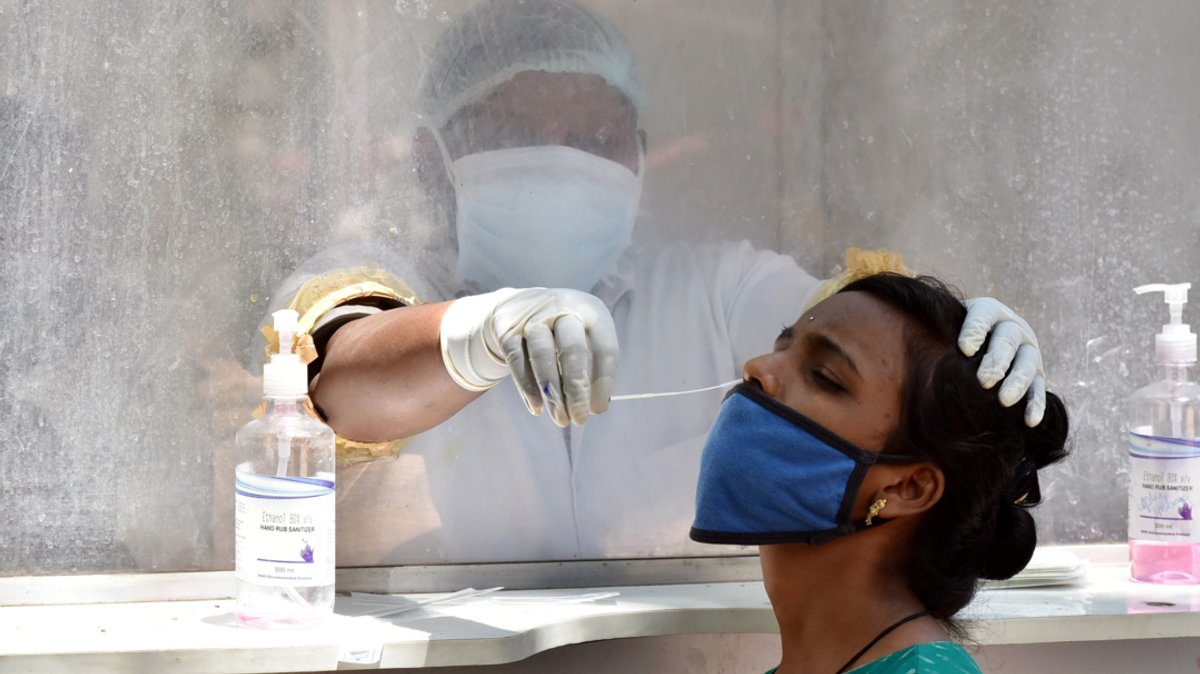 Indien, Hyderabad: Ein Mitarbeiter des Gesundheitswesens nimmt von einer Frau einen Abstrich für einen Corona-Test.