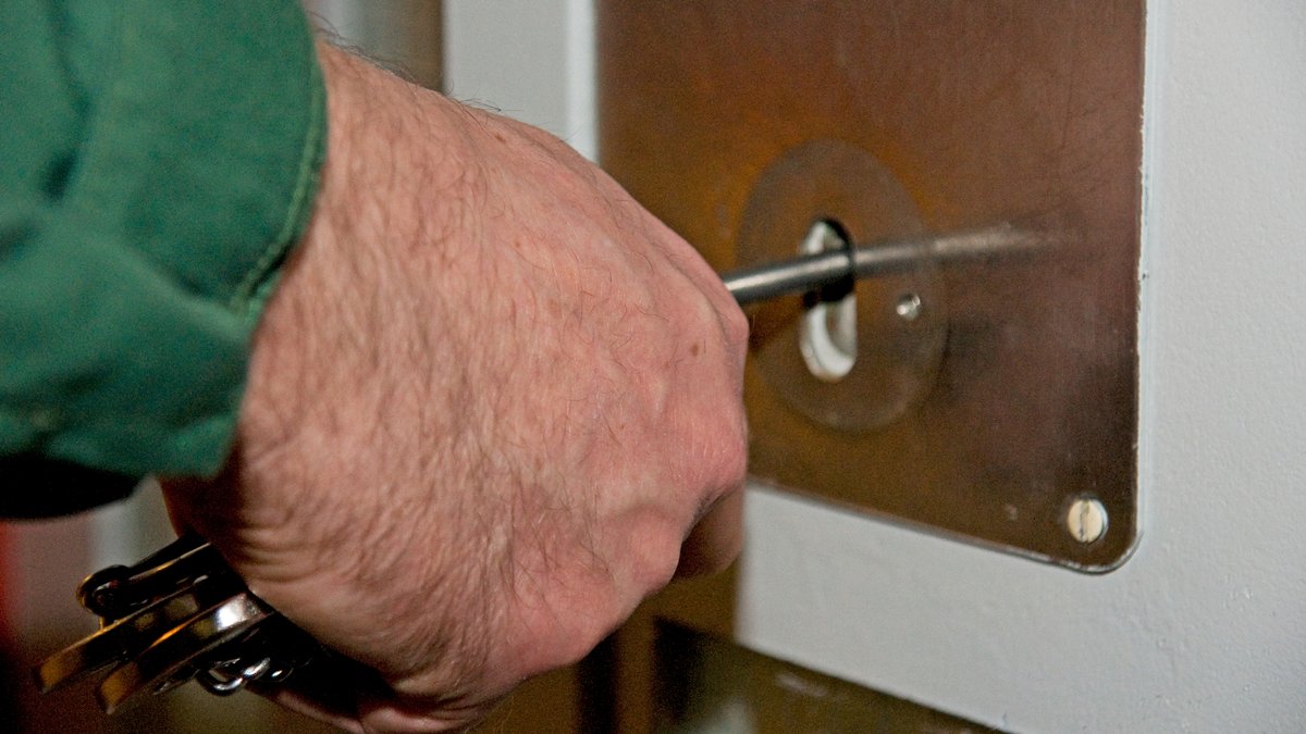 Ein JVA-Mitarbeiter steckt den Schlüssen in eine Zellentür in Stadelheim