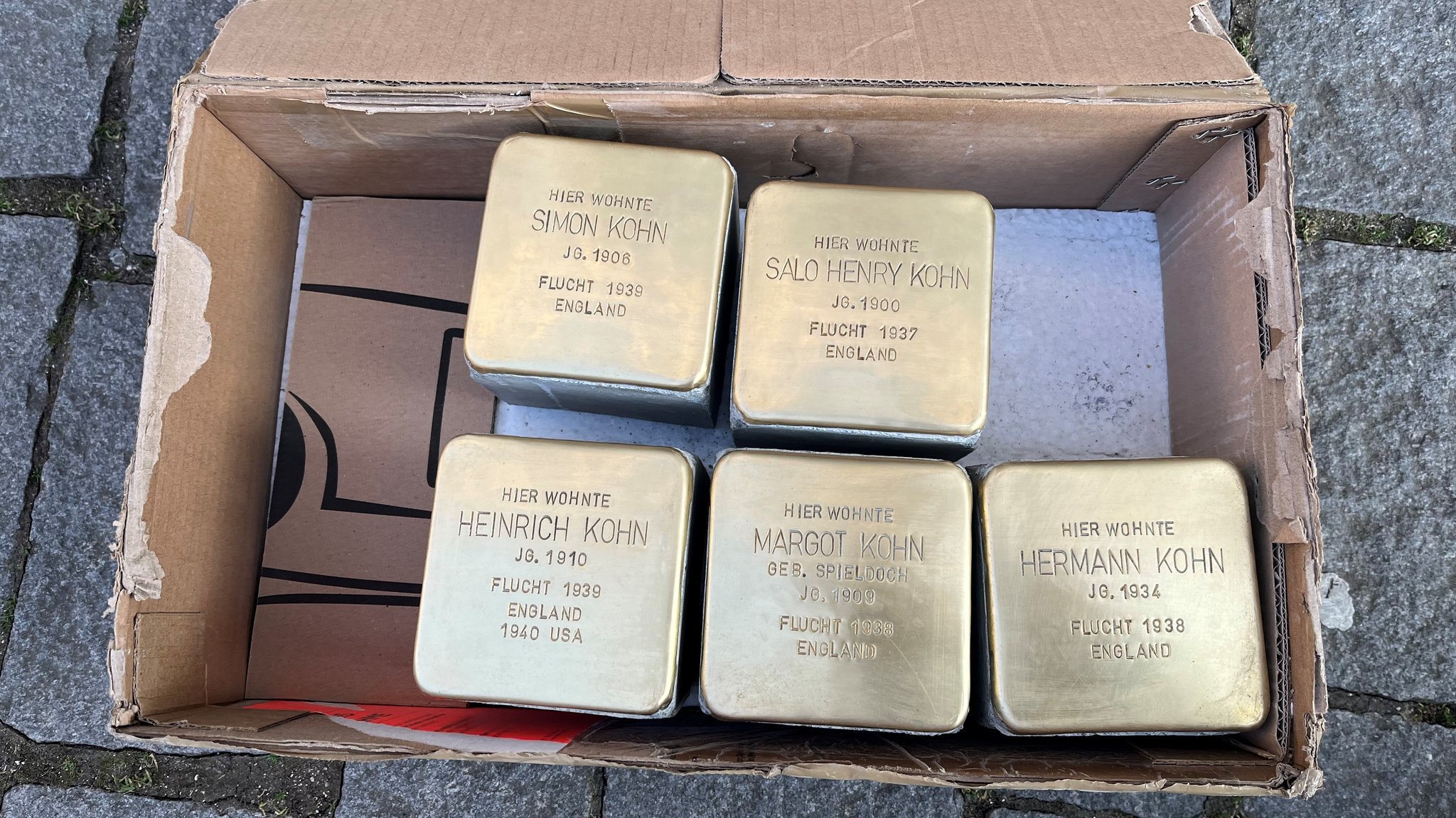 Fünf Stolpersteine für Mitglieder der Familie Kohn liegen in einer Schachtel.