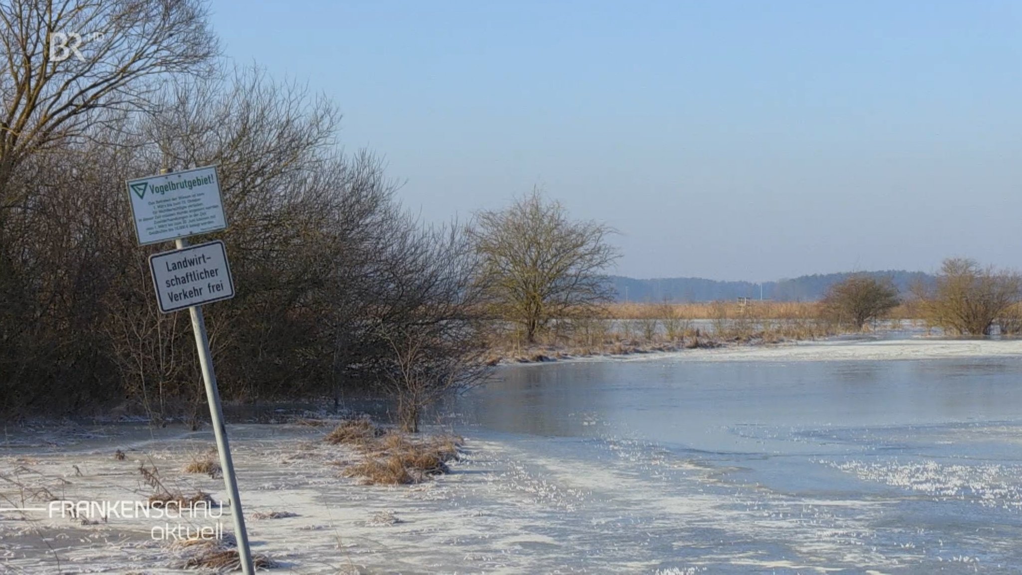 Zwei Schilder an einem See.