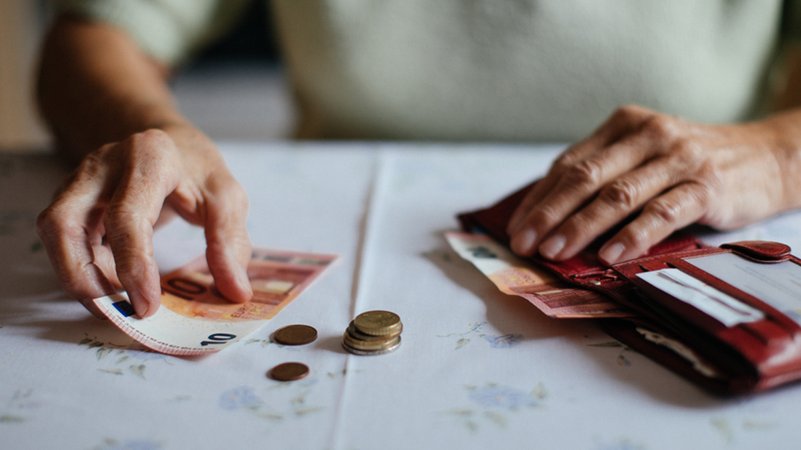 Eine Seniorin hat vor sich auf dem Tisch einen Geldbeutel mit Münzen und Scheinen liegen | Bild: BR/Julia Müller Eine Seniorin hat vor sich auf dem Tisch einen Geldbeutel mit Münzen und Scheinen liegen
