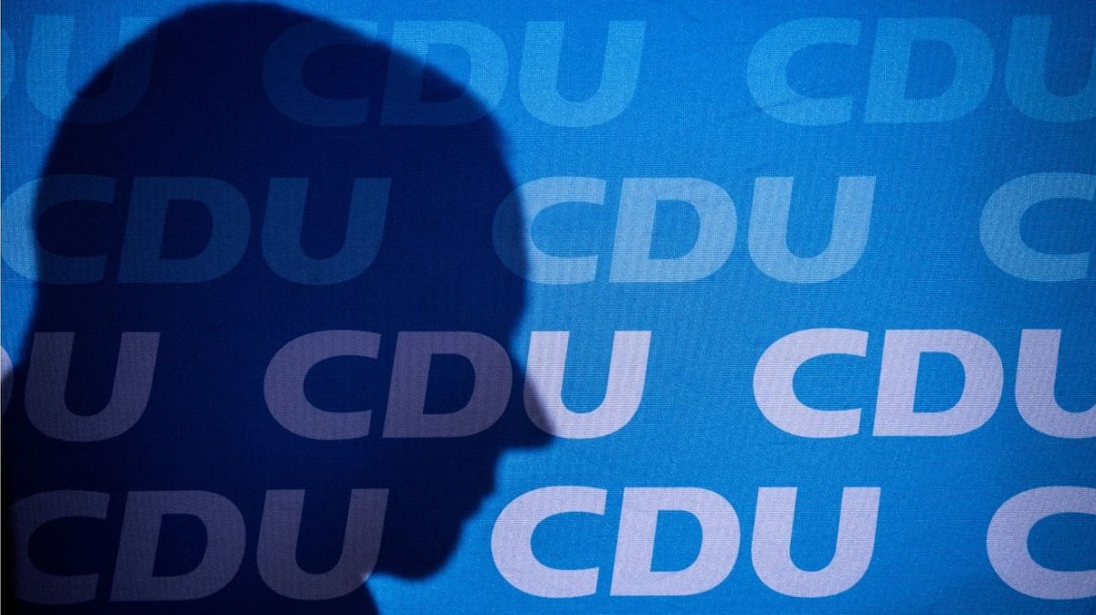 Friedrich Merz wirft einen Schatten auf die CDU-Logos an einer Stellwand