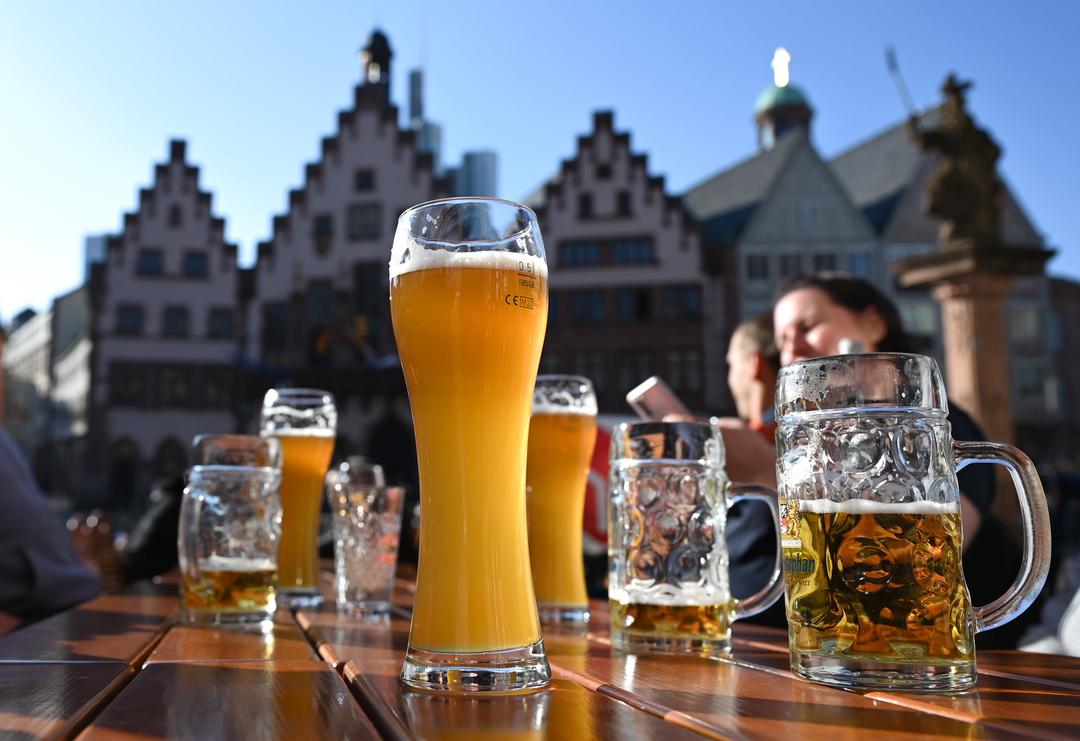 Auf dem Tisch im Außenbereich einer Gaststätte stehen Biergläser in der Sonne. 