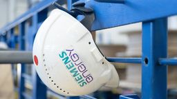 Ein Schutzhelm mit der Aufschrift "Siemens Energy" hängt in einer Werkhalle im Transformatorenwerk Siemens Energy. | Bild:dpa-Bildfunk/Sebastian Kahnert