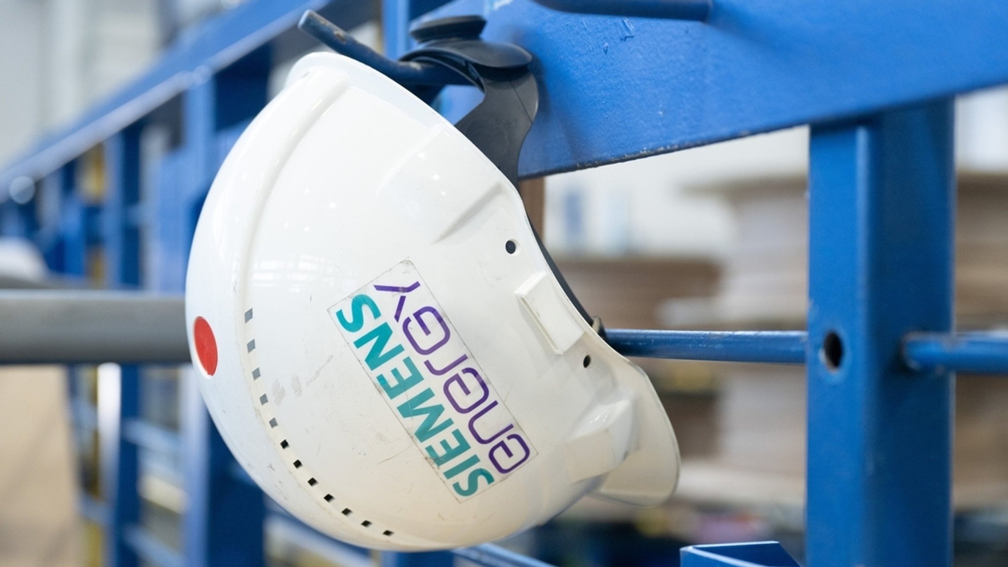 Ein Schutzhelm mit der Aufschrift "Siemens Energy" hängt in einer Werkhalle im Transformatorenwerk Siemens Energy.