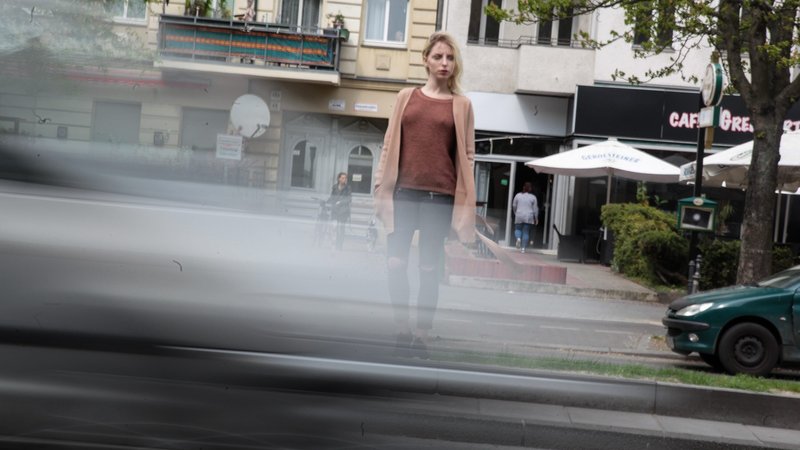 Junge Frau mit langen blonden Haaren steht am Straßenrand mit schnell an ihr vorbeifahrenden Autos | Bild: picture alliance / Rolf Kremming | Rolf Kremming Junge Frau mit langen blonden Haaren steht am Straßenrand mit schnell an ihr vorbeifahrenden Autos