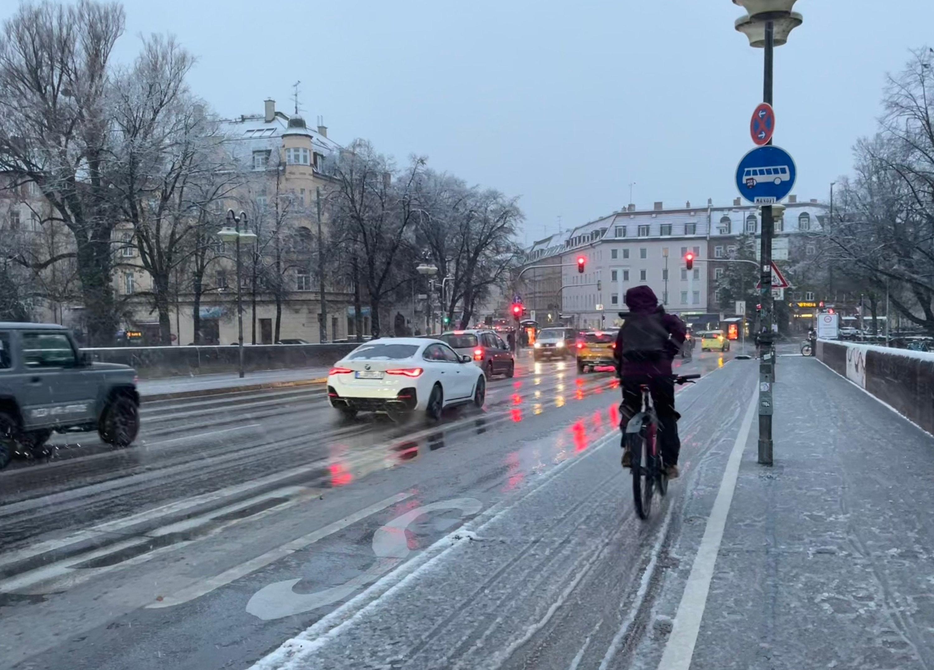 20.11.2024, Bayern, München: Autos und ein Radfahrer sind am Morgen bei Schneematsch ins Münchner Stadtzentrum unterwegs. 