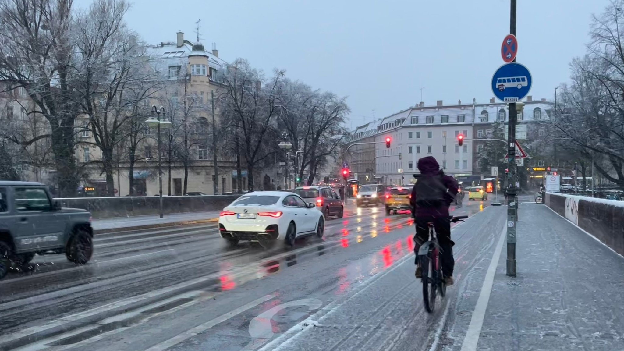 20.11.2024, Bayern, München: Autos und ein Radfahrer sind am Morgen bei Schneematsch ins Münchner Stadtzentrum unterwegs. 