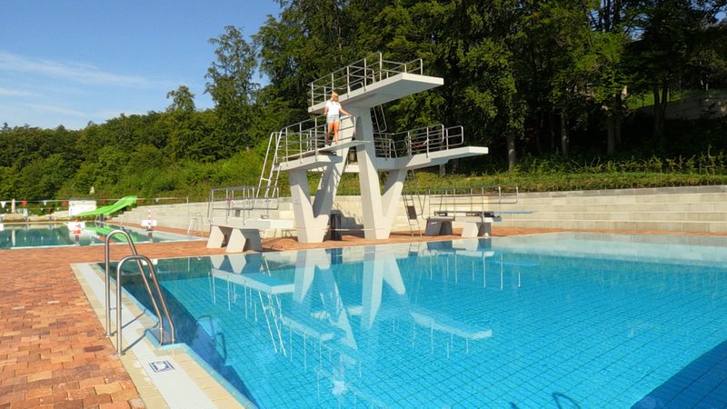 Eine Frau steht auf einem Drei-Meter-Brett in einem Freibad. Das Becken ist leer und es sind keine Menschen da. | Bild: BR/Michelle Balzer Eine Frau steht auf einem Drei-Meter-Brett in einem Freibad. Das Becken ist leer und es sind keine Menschen da.