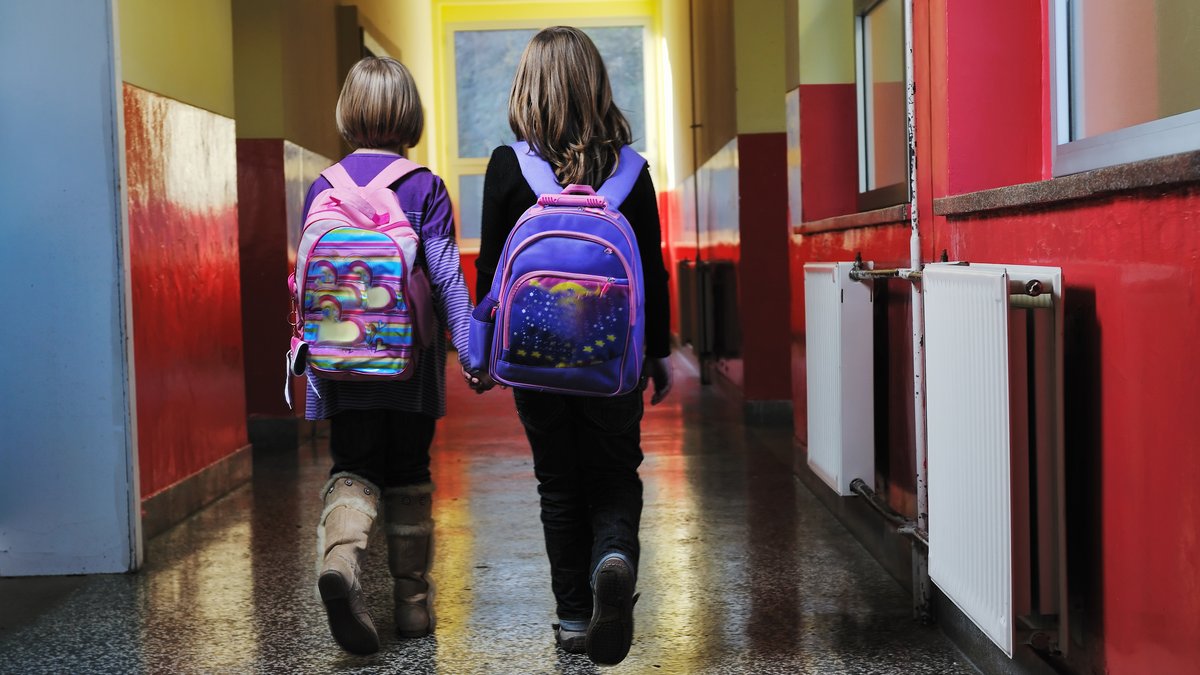 Zwei Schulkinder gehen Gang entlang; das aktuelle Deutsche Schulbarometer zeigt, woran das Schulsystem gerade krankt.
