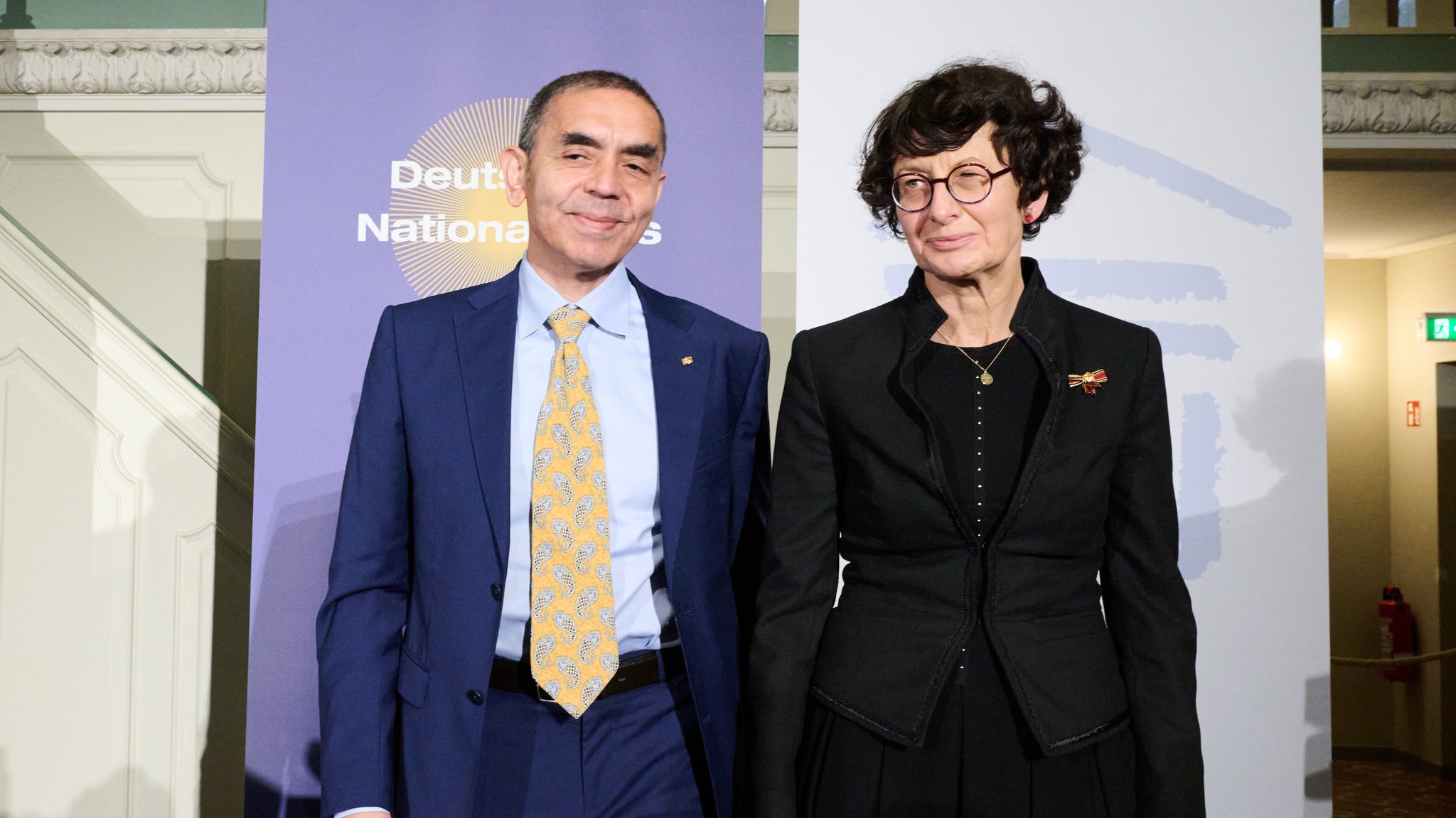 Das Professorenpaar, Gründer und Vorstandsvorsitzende des Unternehmens BioNTech, Ugur Sahin (l) und Özlem Türeci stehen bei der Verleihung des Deutschen Nationalpreises auf der Bühne im französischen Dom am Gendarmentmarkt. Kanzler Merz hatte die Laudatio für das Ehepaar gehalten. 