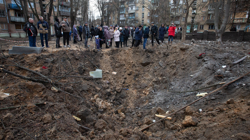 Bewohner Kiews stehen am Neujahrstag um einen Krater, der von einem Raketeneinschlag stammt