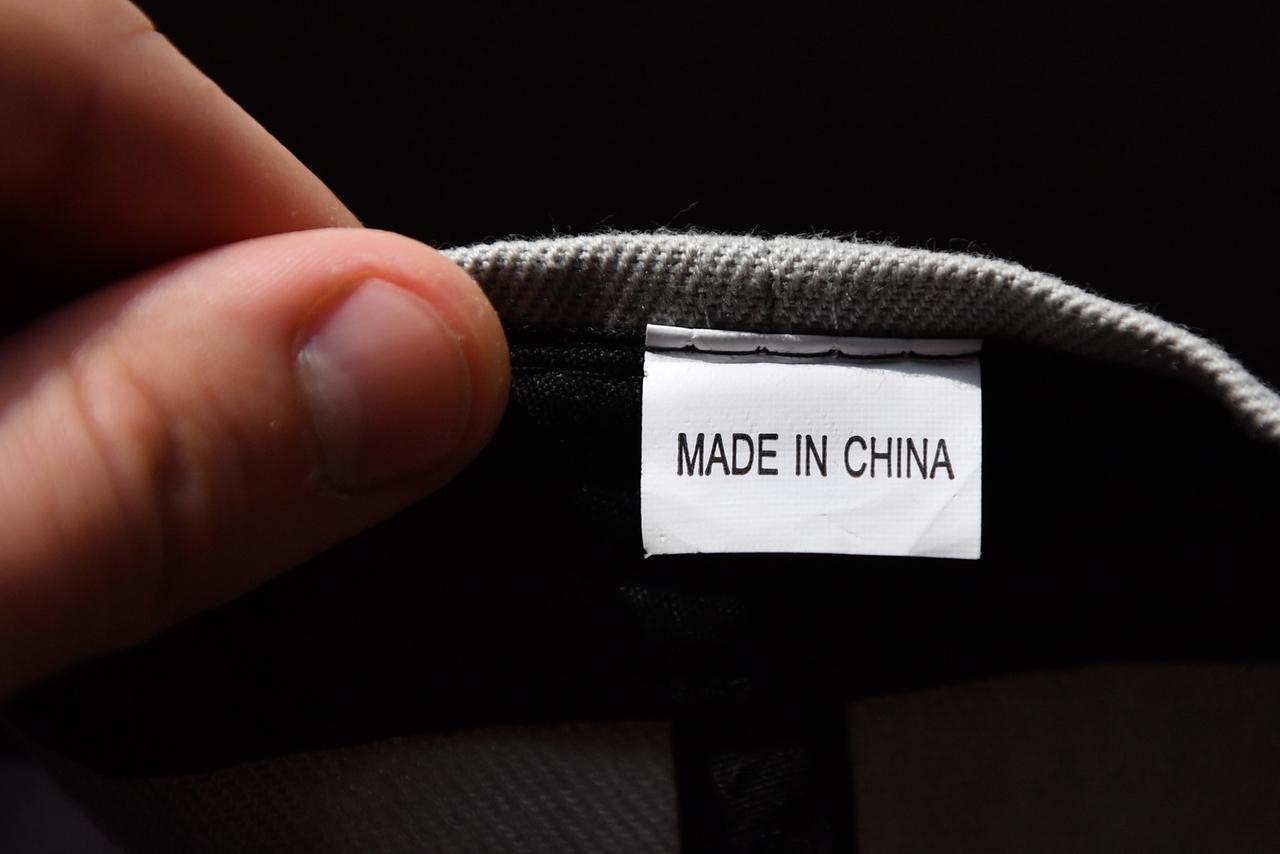 Hand hält ein Etikett mit der Aufschrift "Made in China"