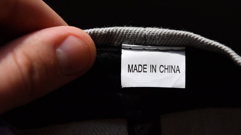 Hand hält ein Etikett mit der Aufschrift "Made in China"