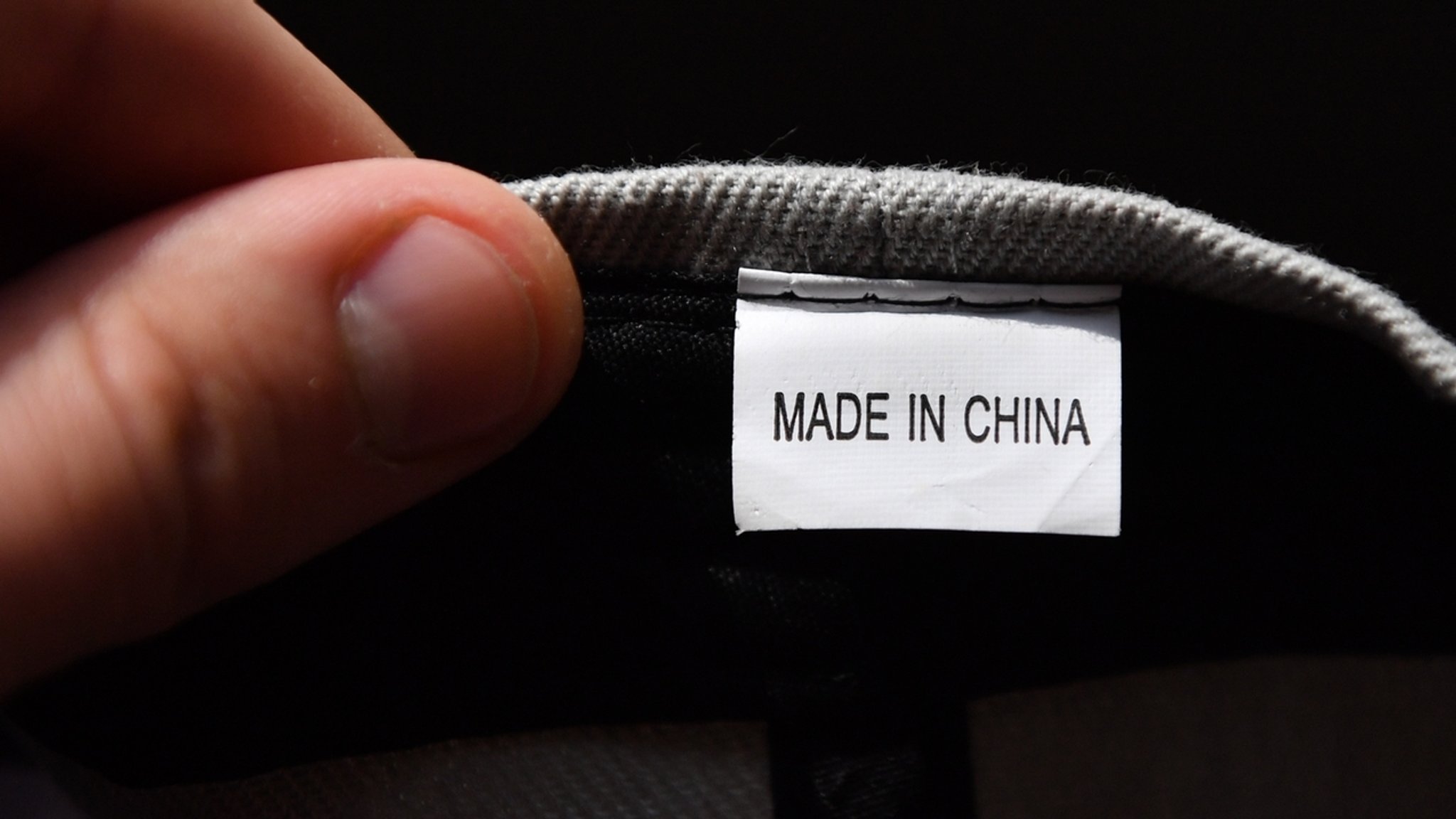 Hand hält ein Etikett mit der Aufschrift "Made in China"