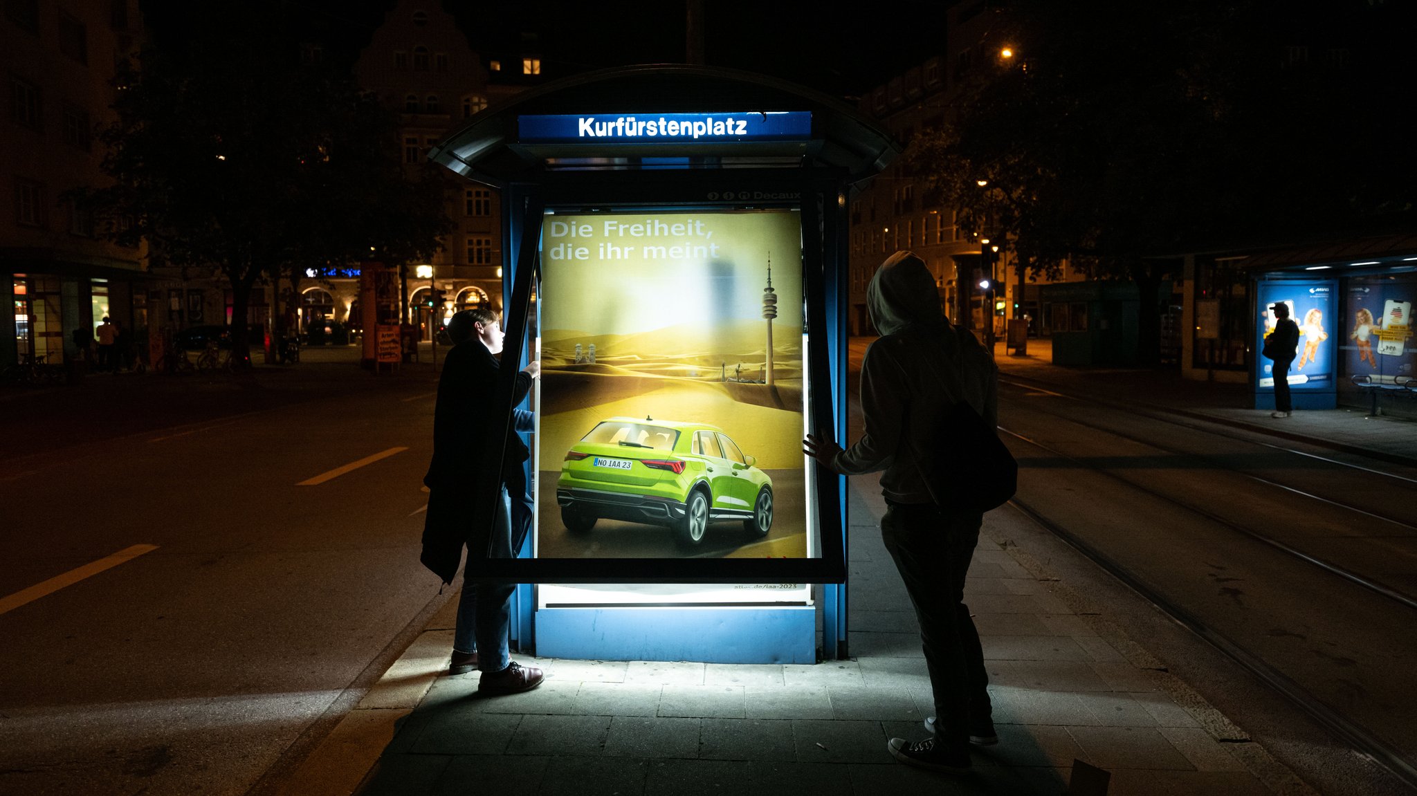 Aktivisten der Nichtregierungsorganisation Attac bringen als Protest gegen die IAA Mobility kritische Persiflagen von Autowerbung an.