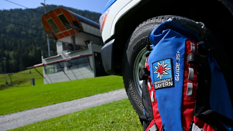 Ein Rucksack mit dem Logo der Bergwacht Bayern steht während einer Pressekonferenz an der Bergstation der Hocheck-Bahn (Hockeck-Express). | Bild: picture alliance/dpa | Sven Hoppe Ein Rucksack mit dem Logo der Bergwacht Bayern steht während einer Pressekonferenz an der Bergstation der Hocheck-Bahn (Hockeck-Express).