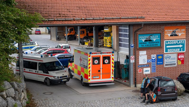 Ein Krankenwagen steht in der Einfahrt eines Unternehmens. Bei einem Unfall in einer Entsorgungsfirma in Oberbayern sind drei Männer in einem Kanalsystem ertrunken. Foto: Peter Kneffel/dpa - ACHTUNG: Die Kennzeichennummer aus rechtlichen Gründen gepixelt +++ dpa-Bildfunk +++