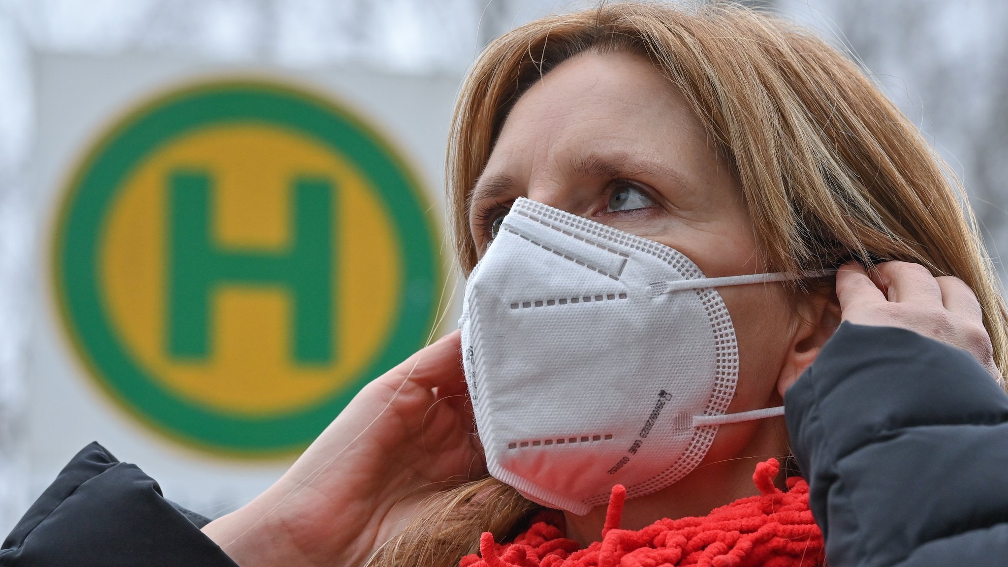 Eine Frau trägt eine FFP2 Schutzmaske an einer Bushaltestelle (Symbolbild).