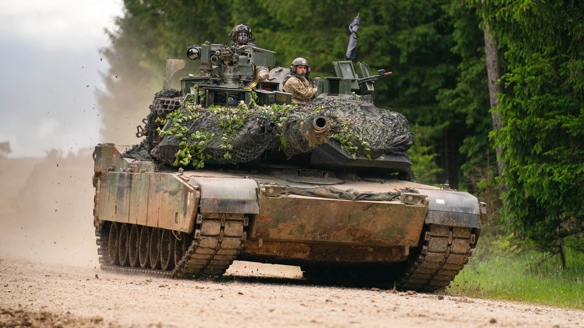 Ein Panzer des Typs M1 Abrams der US-Armee fährt während einer multinationalen Übung auf einem Truppenübungsplatz über eine Straße.